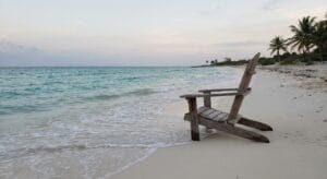 Empty wooden chair facing calm turquoise waters on a quiet Cozumel beach at dawn, symbolizing contemplation and new possibilities in depression treatment