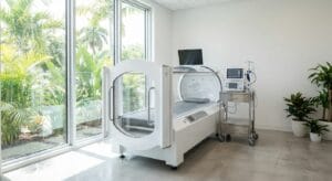 Hyperbaric oxygen therapy chamber in a medical treatment room with natural light and tropical views at Iboga Wellness Institute in Cozumel