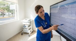 Physician reviewing cardiac ECG monitor during pre-treatment medical screening at ibogaine clinic