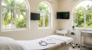 Medical examination room in licensed Cozumel clinic with cardiac monitoring equipment and natural tropical daylight, representing physician-supervised ibogaine treatment setting