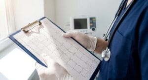 Medical professional reviewing a 12-lead ECG printout in a clinical setting, representing thorough medical screening before ibogaine treatment