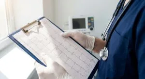 Medical professional reviewing a 12-lead ECG printout in a clinical setting, representing thorough medical screening before ibogaine treatment
